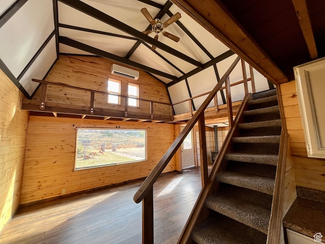interior space with wood walls, wood-type flooring, lofted ceiling with beams, and a wall mounted air conditioner