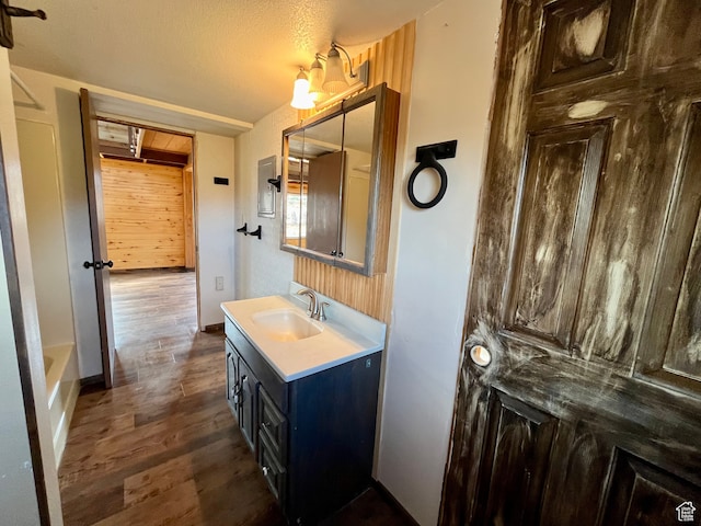 bathroom with hardwood / wood-style floors, vanity, a textured ceiling, and a tub