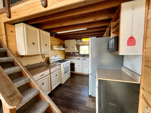 kitchen featuring white gas stove, white cabinetry, sink, dark hardwood / wood-style floors, and wooden walls