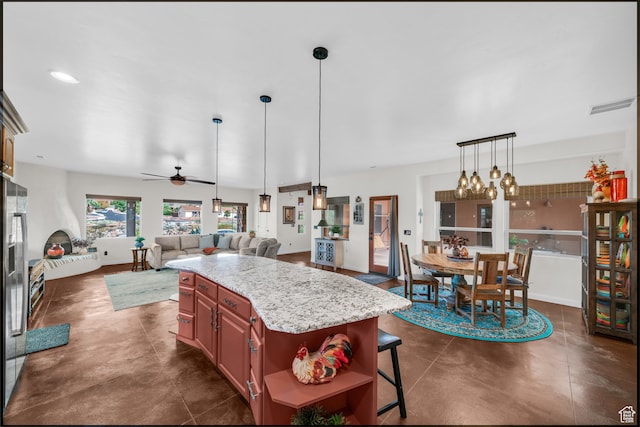896 E Mesa Vista Dr, Ivins, UT 84738 - kitchen featuring light stone counters, a kitchen bar, ceiling fan with notable chandelier, decorative light fixtures, and a kitchen island