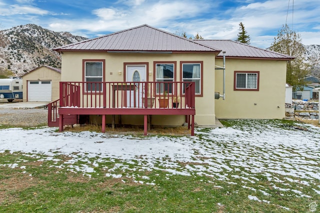 snow covered property with an outbuilding, a garage, and a deck with mountain view