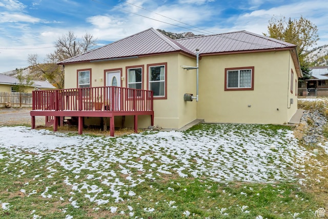 snow covered rear of property with a deck