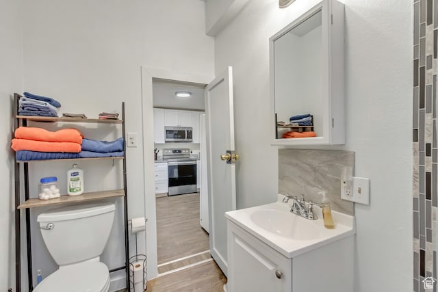 bathroom featuring toilet, decorative backsplash, vanity, and wood-type flooring