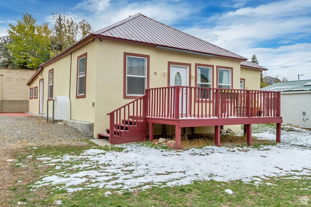 snow covered back of property featuring a wooden deck