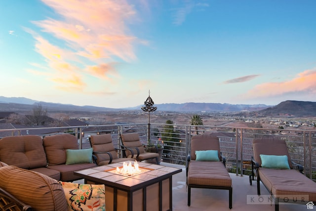 patio terrace at dusk featuring a mountain view, an outdoor living space with a fire pit, and a balcony