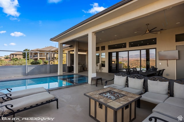 view of pool with an outdoor living space with a fire pit, a patio area, and ceiling fan