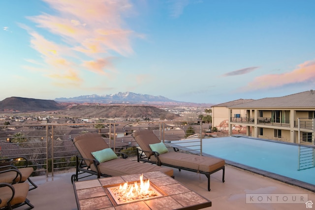 pool at dusk with a mountain view and an outdoor fire pit