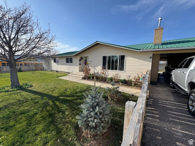 back of property with a chimney, brick siding, fence, metal roof, and a lawn