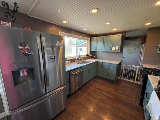 kitchen with recessed lighting, appliances with stainless steel finishes, light countertops, a sink, and dark wood-style floors