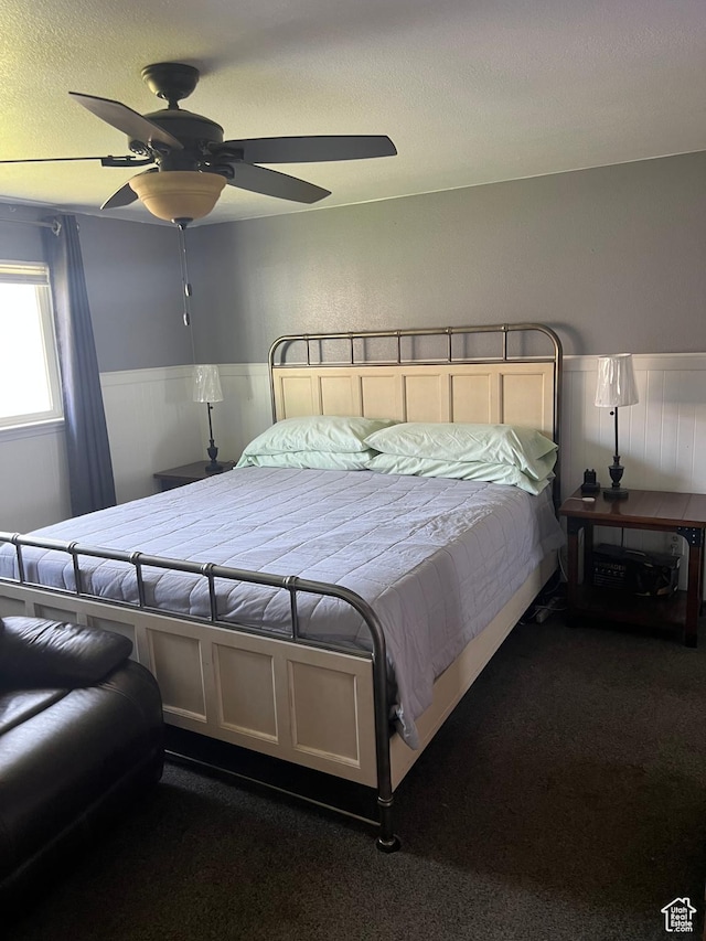carpeted bedroom with ceiling fan and wainscoting