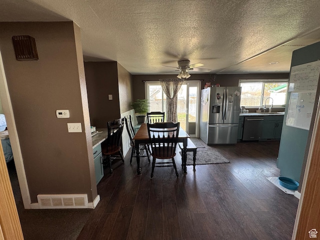 dining room with dark wood-type flooring, ceiling fan, visible vents, and a textured ceiling