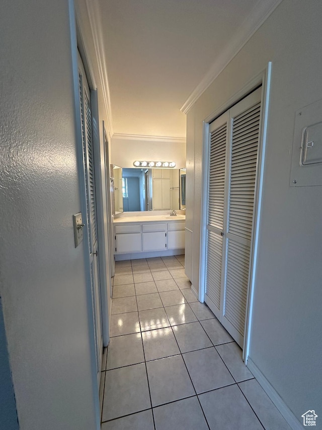 corridor with ornamental molding, light tile patterned floors, and a sink