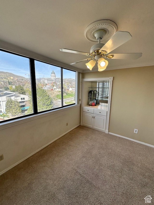 spare room with light carpet, a ceiling fan, and baseboards