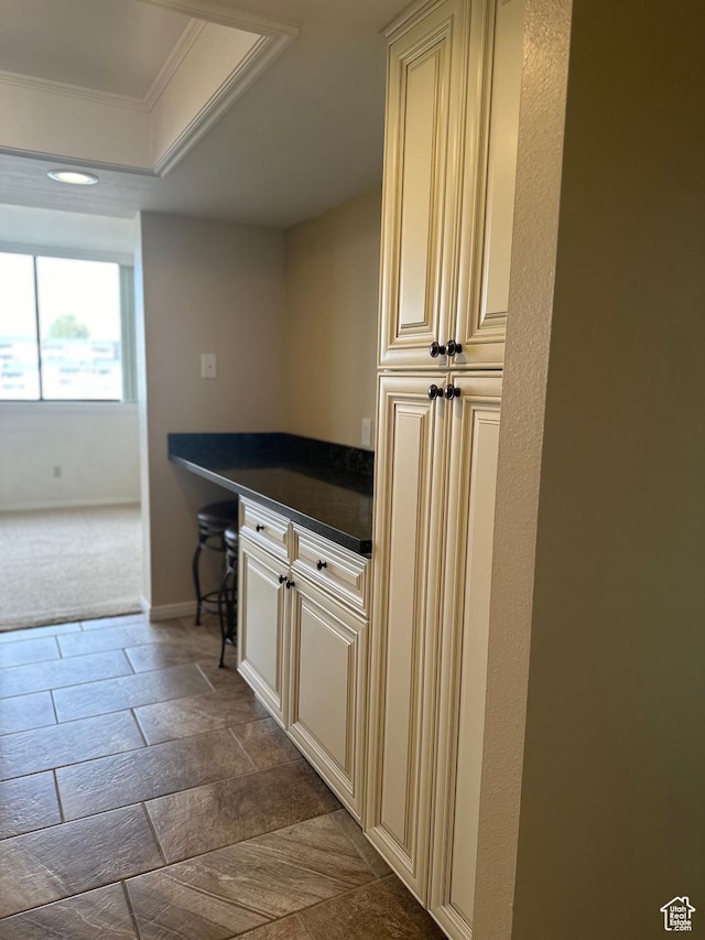 bar area with ornamental molding, baseboards, and dark colored carpet