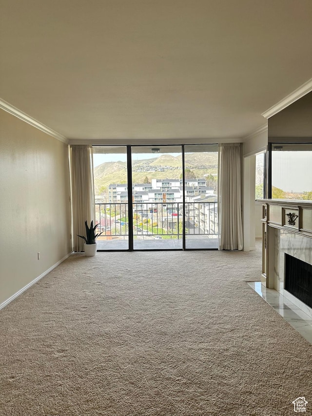 unfurnished living room featuring a tiled fireplace, ornamental molding, carpet, and a wealth of natural light