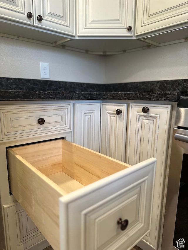 detailed view of white cabinets and dark stone counters