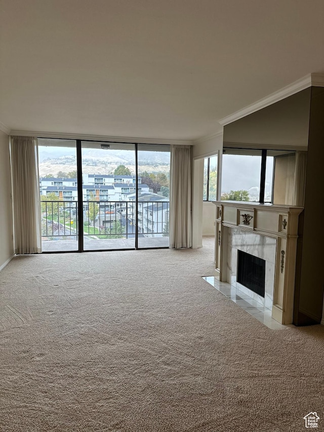 unfurnished living room with carpet floors, ornamental molding, a fireplace, and expansive windows