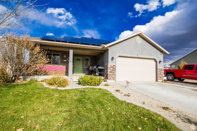 ranch-style house featuring covered porch, solar panels, a garage, and a front lawn
