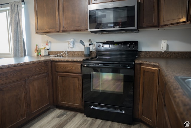 kitchen featuring dark brown cabinets, light hardwood / wood-style flooring, and black electric range oven