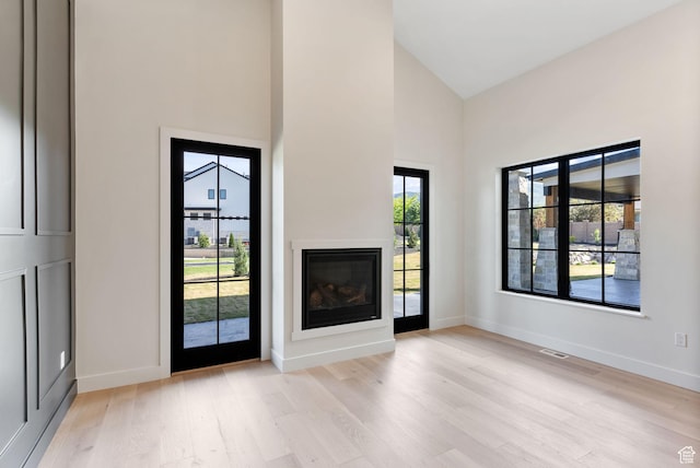 231 S Wiltshire Ln, Saratoga Springs, UT 84045 - unfurnished living room featuring light wood finished floors, high vaulted ceiling, baseboards, and a glass covered fireplace