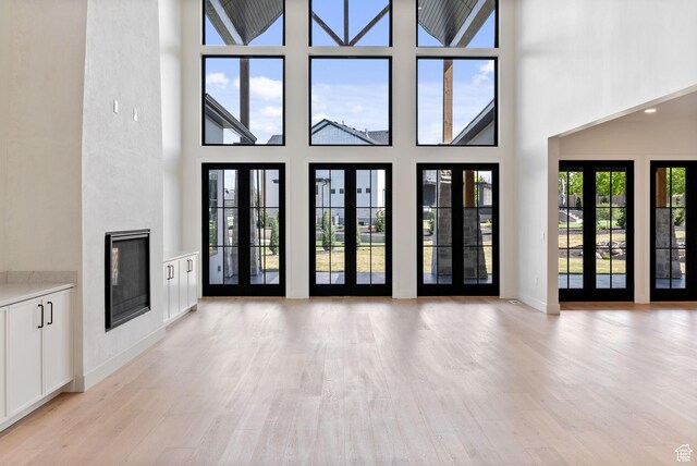 231 S Wiltshire Ln, Saratoga Springs, UT 84045 - unfurnished living room with a towering ceiling, light wood-type flooring, and a fireplace