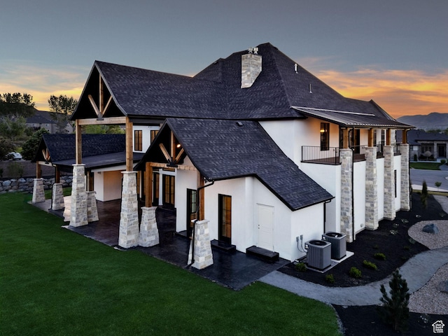 231 S Wiltshire Ln, Saratoga Springs, UT 84045 - back of property at dusk featuring stucco siding, a shingled roof, a yard, and a patio area