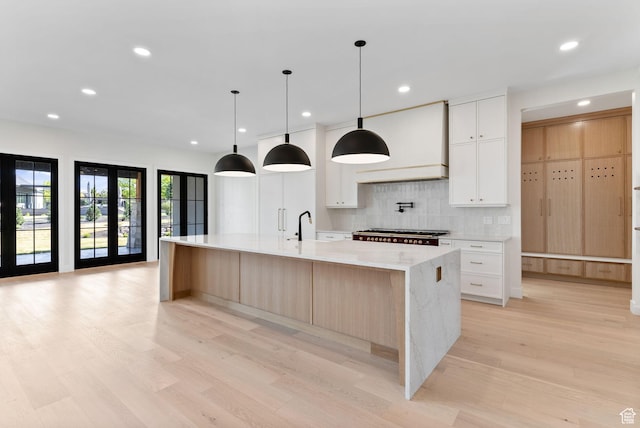 231 S Wiltshire Ln, Saratoga Springs, UT 84045 - kitchen with light wood-type flooring, tasteful backsplash, custom exhaust hood, a spacious island, and recessed lighting