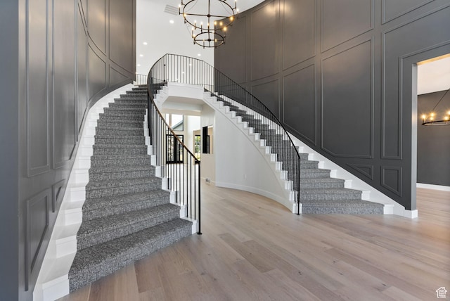 231 S Wiltshire Ln, Saratoga Springs, UT 84045 - stairs with a chandelier, a decorative wall, wood finished floors, baseboards, and a high ceiling