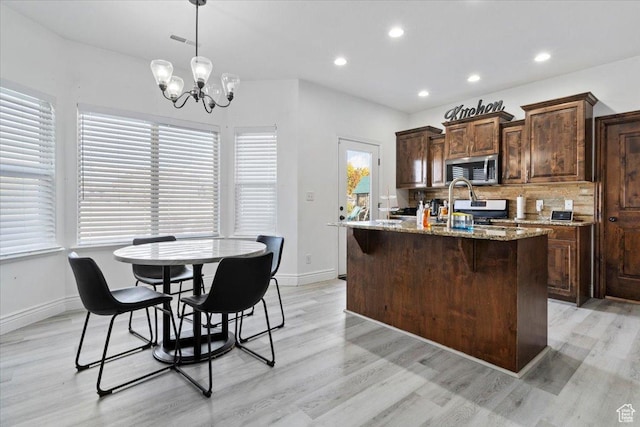 787 E 1950 S, Lehi, UT 84043 - kitchen with appliances with stainless steel finishes, light wood-type flooring, a center island with sink, decorative backsplash, and baseboards