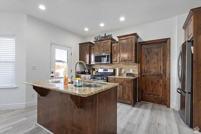 787 E 1950 S, Lehi, UT 84043 - kitchen featuring stainless steel appliances, light wood-style floors, decorative backsplash, a sink, and a center island with sink
