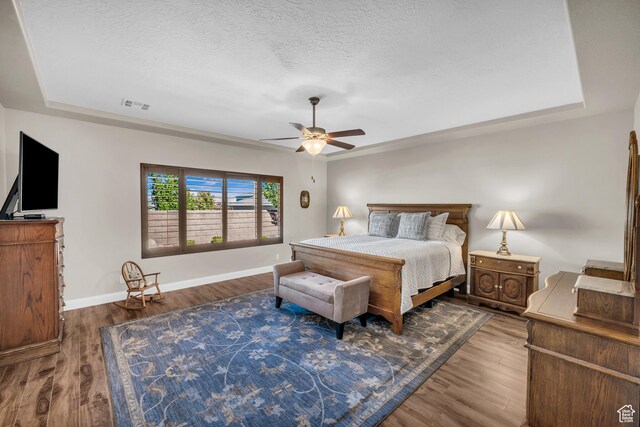 3277 E 3180 S, St George, UT 84790 - bedroom featuring wood finished floors, baseboards, a tray ceiling, ceiling fan, and a textured ceiling