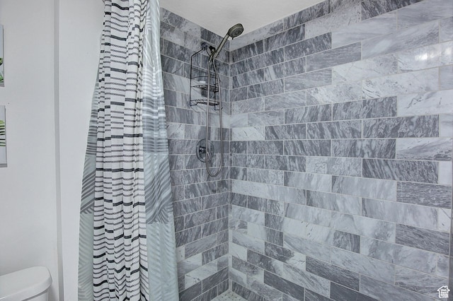 bathroom featuring toilet and a tile shower