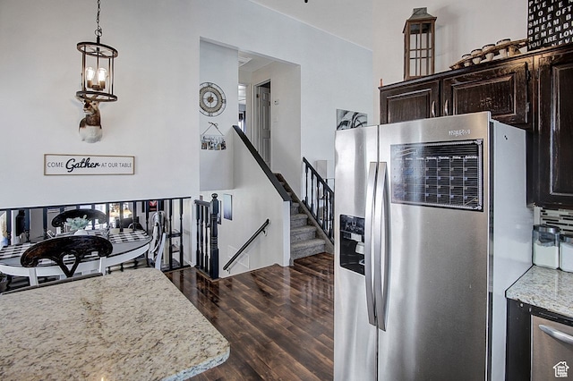 kitchen with light stone counters, dark hardwood / wood-style floors, decorative light fixtures, dark brown cabinets, and stainless steel fridge