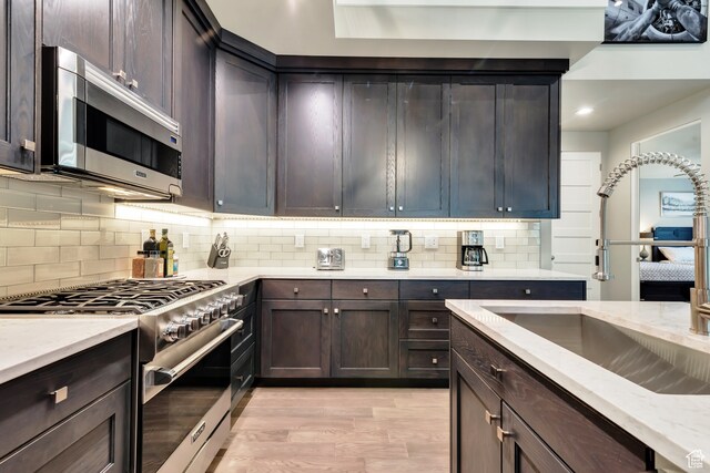 10005 N Meer Cir, Heber City, UT 84032 - kitchen with tasteful backsplash, appliances with stainless steel finishes, dark brown cabinets, sink, and light hardwood / wood-style flooring
