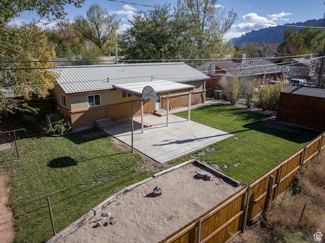 321 Park Rd, Moab, UT 84532 - rear view of house featuring brick siding, a patio, a mountain view, a fenced backyard, and a metal roof