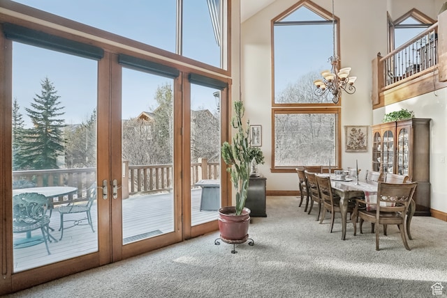 interior space with a notable chandelier, a healthy amount of sunlight, carpet floors, and french doors