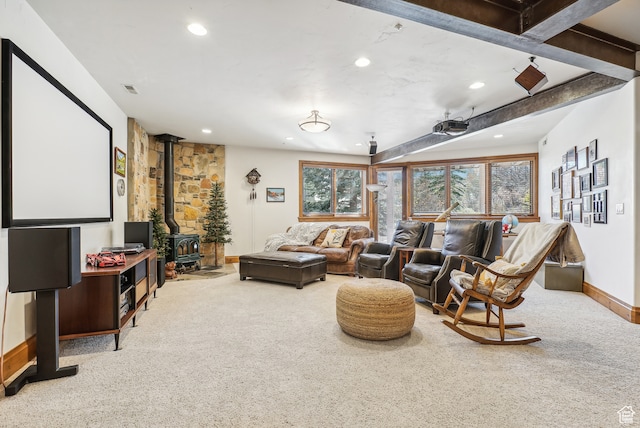 carpeted home theater room with beam ceiling and a wood stove