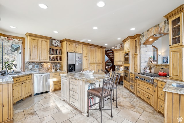 kitchen with tasteful backsplash, light stone counters, stainless steel appliances, sink, and a center island