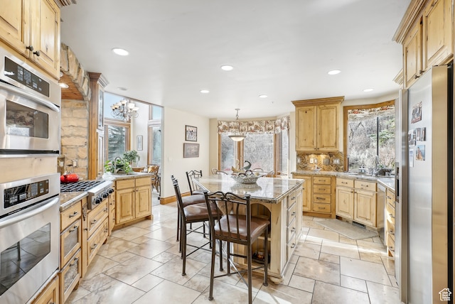 kitchen featuring backsplash, hanging light fixtures, appliances with stainless steel finishes, a kitchen island, and a kitchen bar