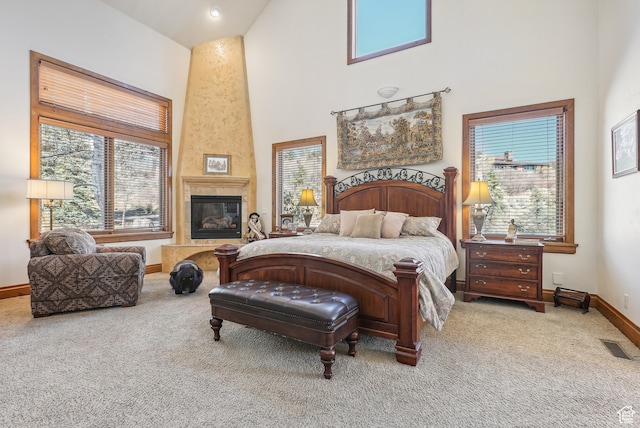 carpeted bedroom with a fireplace, a towering ceiling, and multiple windows