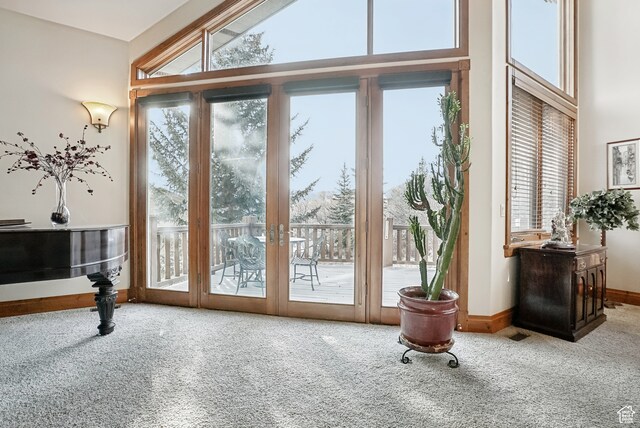 doorway to outside with carpet floors and high vaulted ceiling