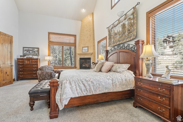 carpeted bedroom featuring a fireplace and high vaulted ceiling