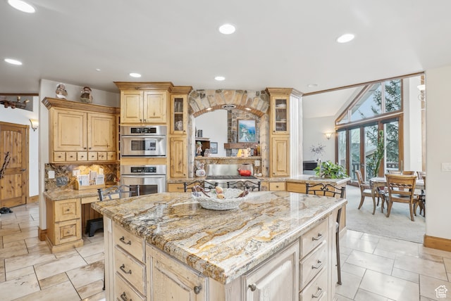 kitchen featuring a breakfast bar area, light stone countertops, a center island, and stainless steel double oven