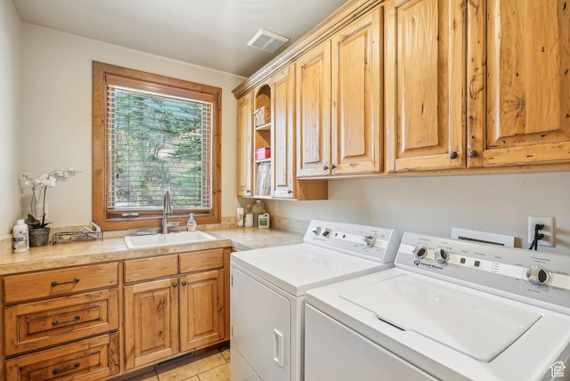 clothes washing area featuring separate washer and dryer, sink, light tile patterned floors, and cabinets