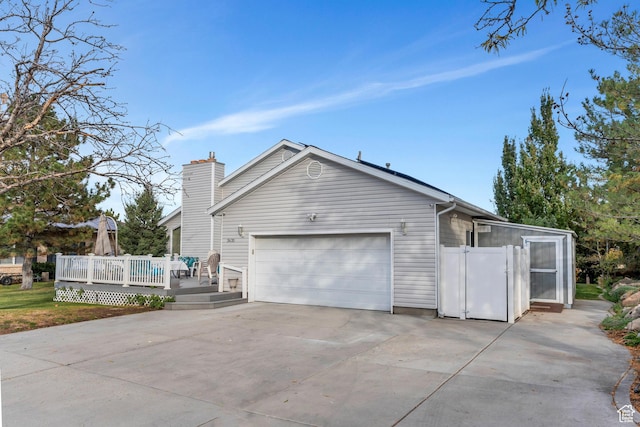 3635 S Arbor Park Dr, Magna, UT 84044 - view of side of property featuring a wooden deck, a garage, concrete driveway, and a chimney