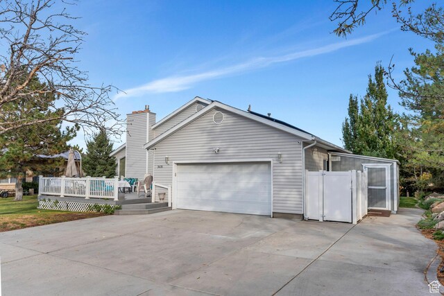 3635 S Arbor Park Dr, Magna, UT 84044 - view of side of property featuring a wooden deck, a garage, concrete driveway, and a chimney