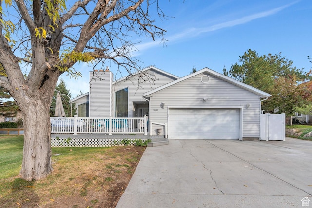 3635 S Arbor Park Dr, Magna, UT 84044 - view of front of property with an attached garage, a wooden deck, concrete driveway, a front lawn, and a chimney