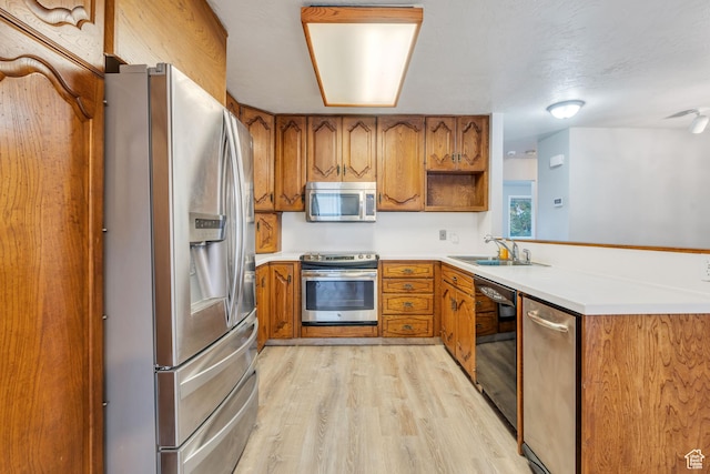 3635 S Arbor Park Dr, Magna, UT 84044 - kitchen with appliances with stainless steel finishes, brown cabinetry, light wood-style flooring, and a sink