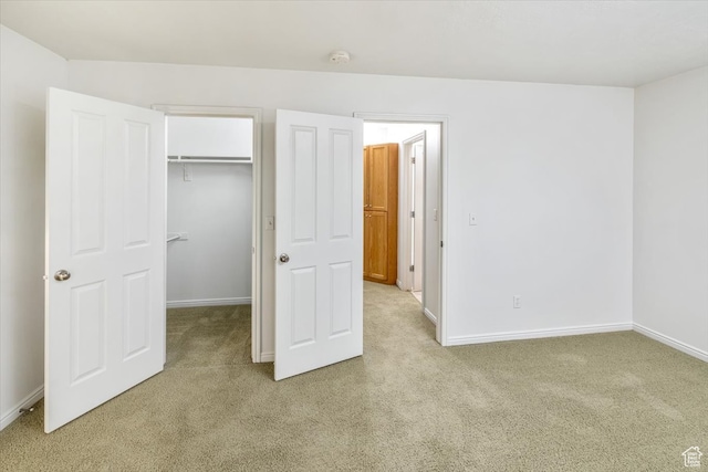 unfurnished bedroom with light colored carpet and a closet