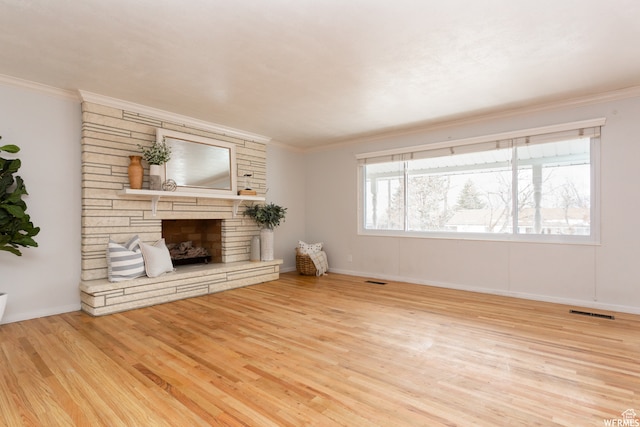 unfurnished living room with a stone fireplace, light wood-type flooring, and crown molding
